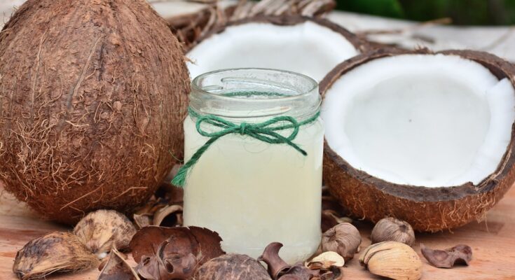 two coconuts on whole one cut in half and a jar of coconut oil